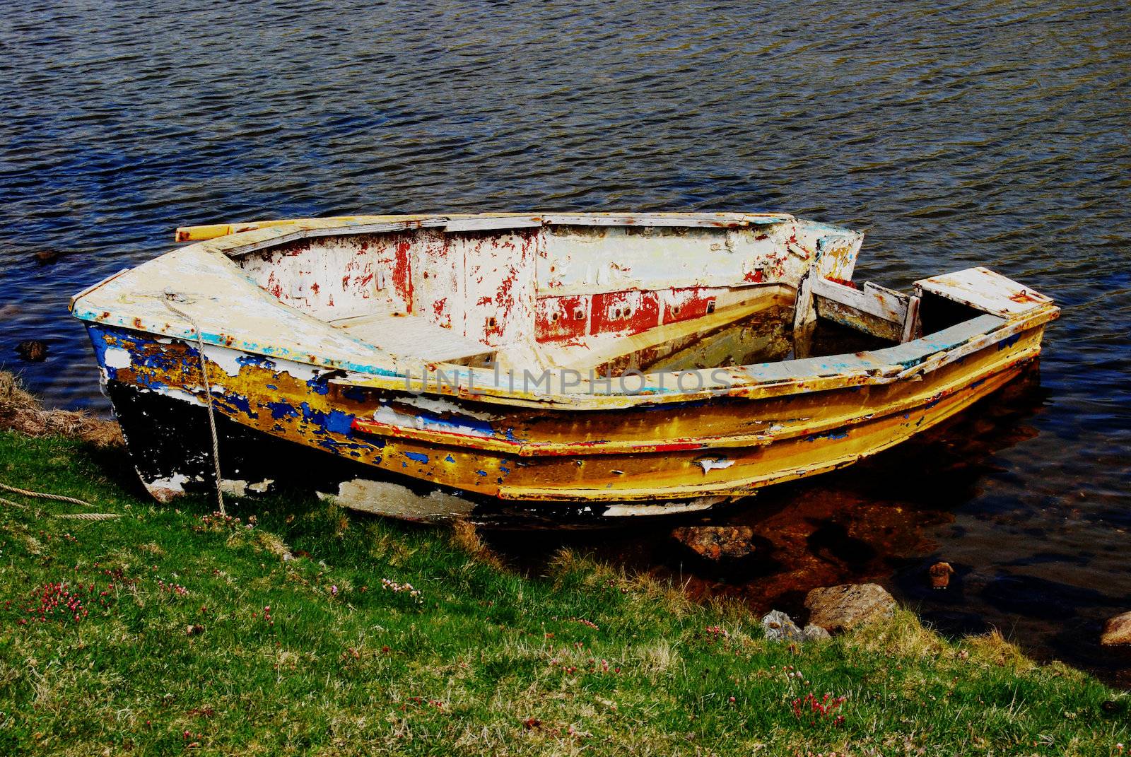 old boat tied on a coastline with a leak