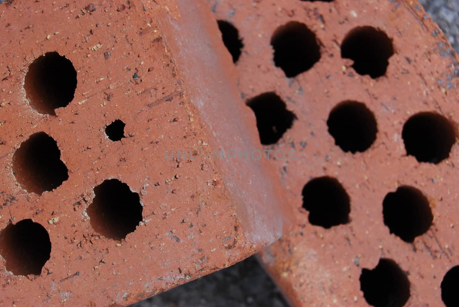 closeup of two red brick stones with holes