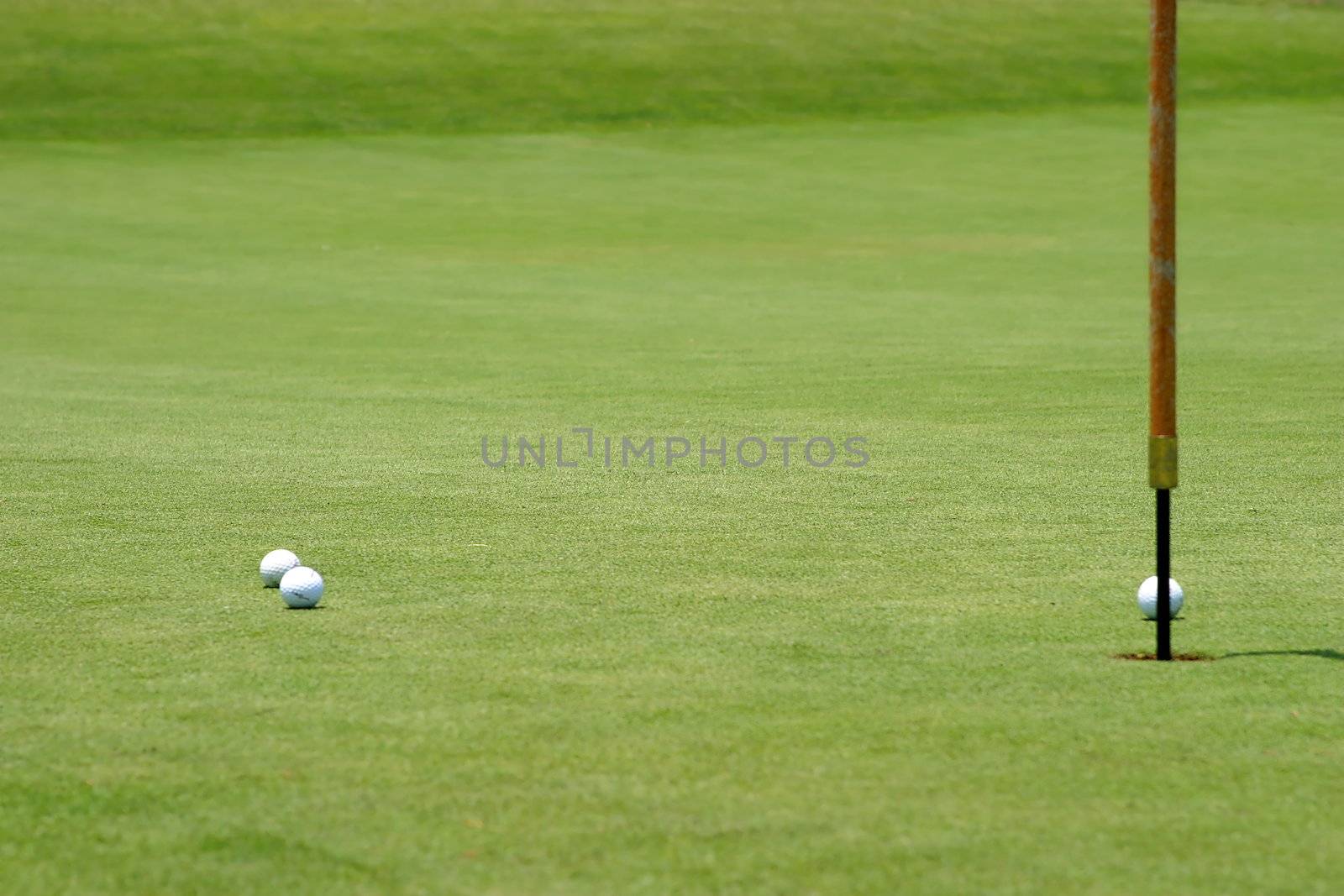 Three golf balls near the flagstick on the green.