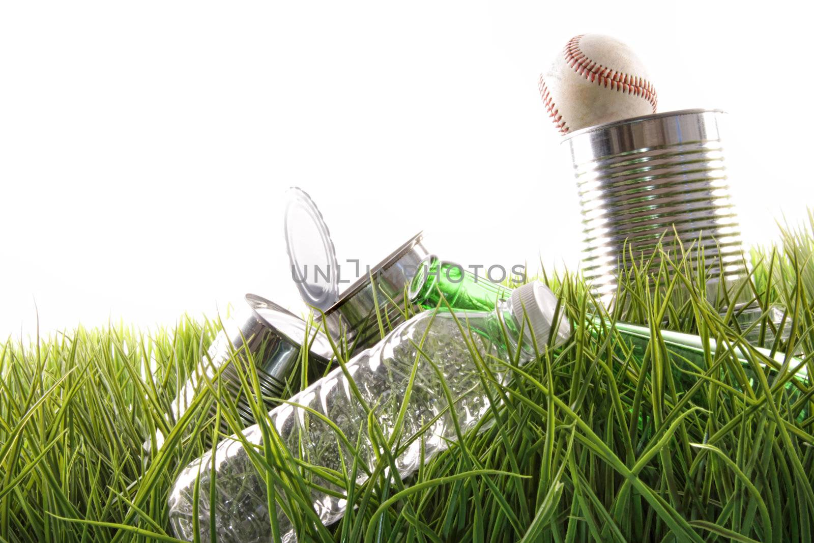 Empty food cans, bottles and baseball laying in grass
