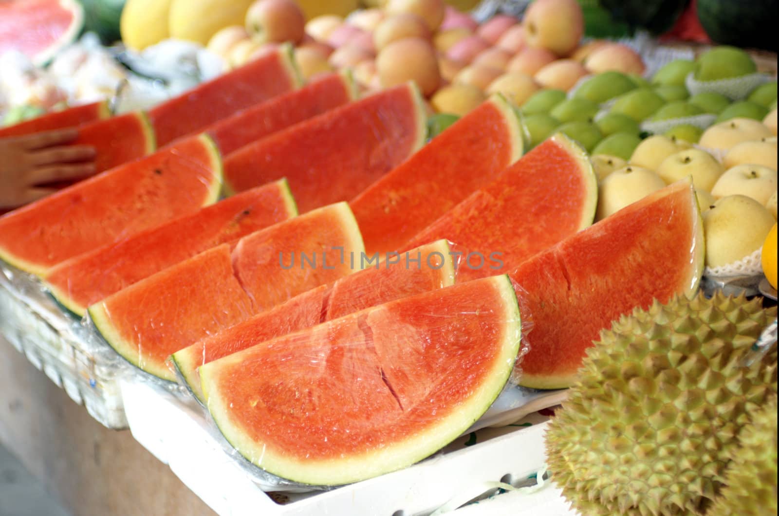 Fresh watermelon, already cut into quarters, ready for sale on market stall. 