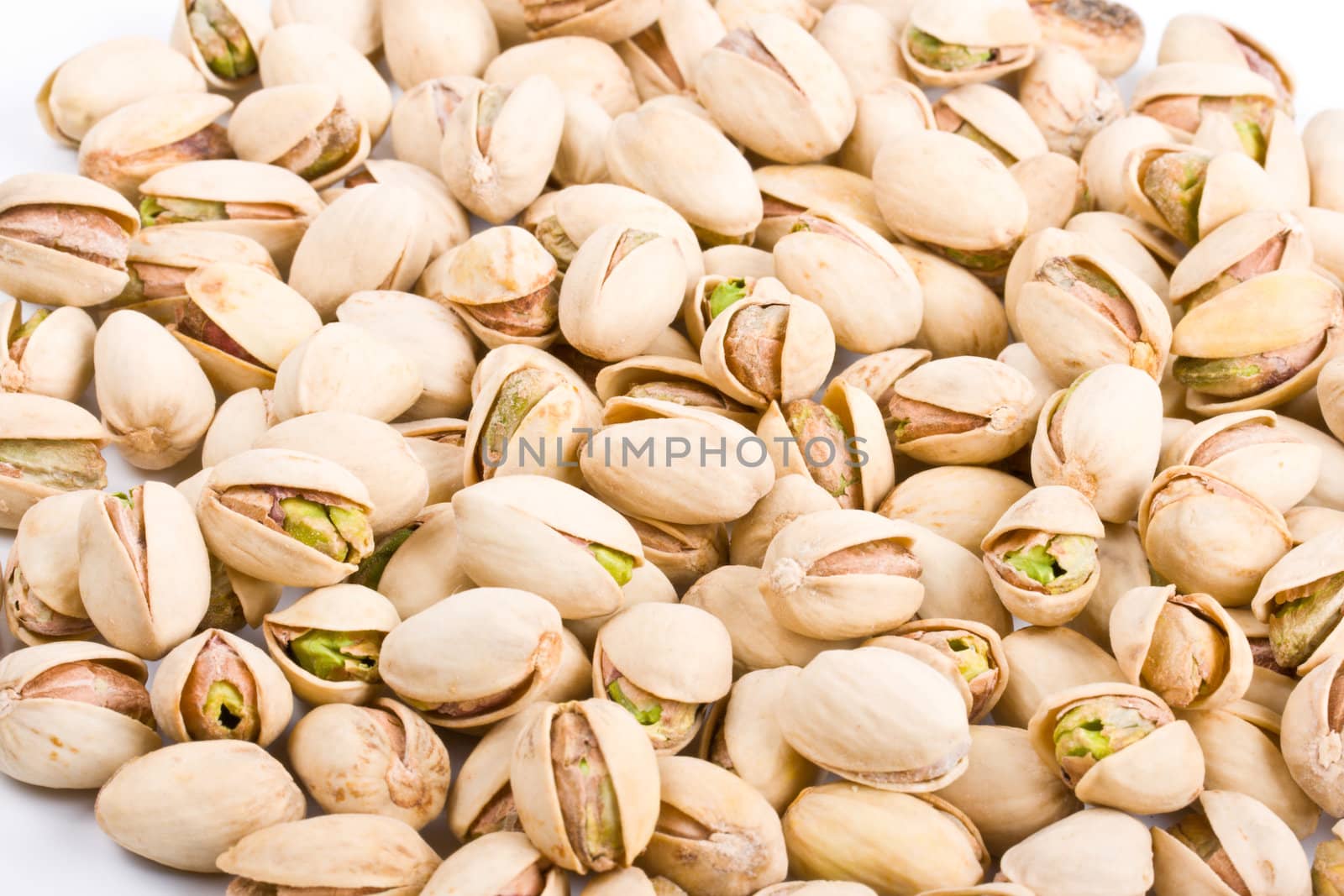 Pile of pistachio nuts close up by dimol