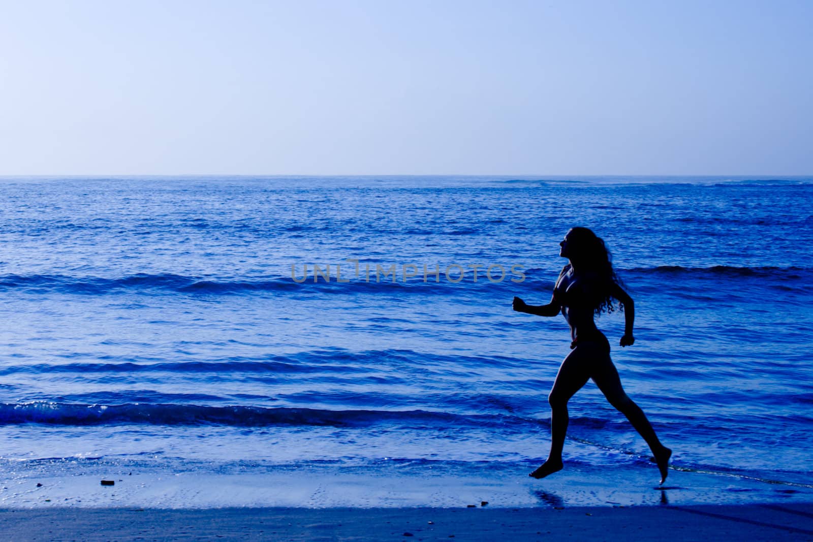 Healthy life concept - sporty woman running along beach in the morning