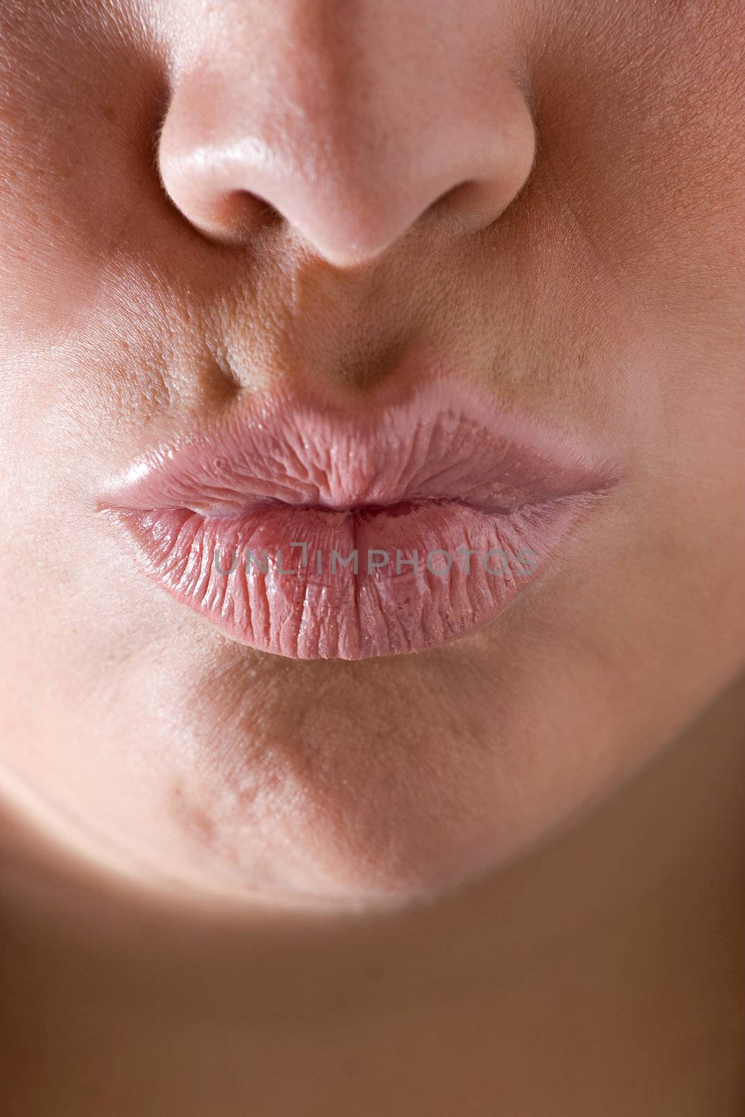 Closeup of a womans full lips puckered up and ready to kiss.