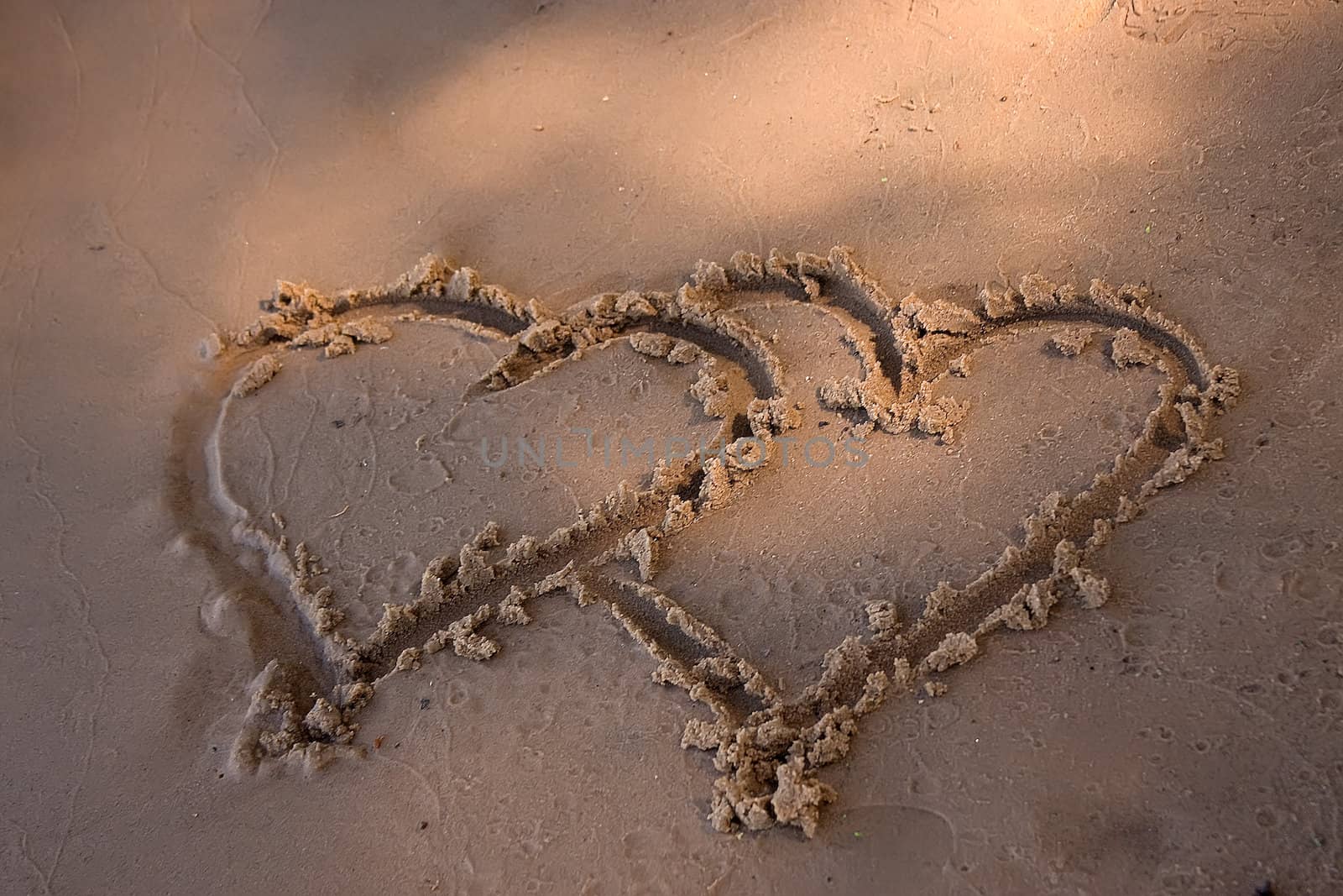Double hearts painted on the yellow sand 
