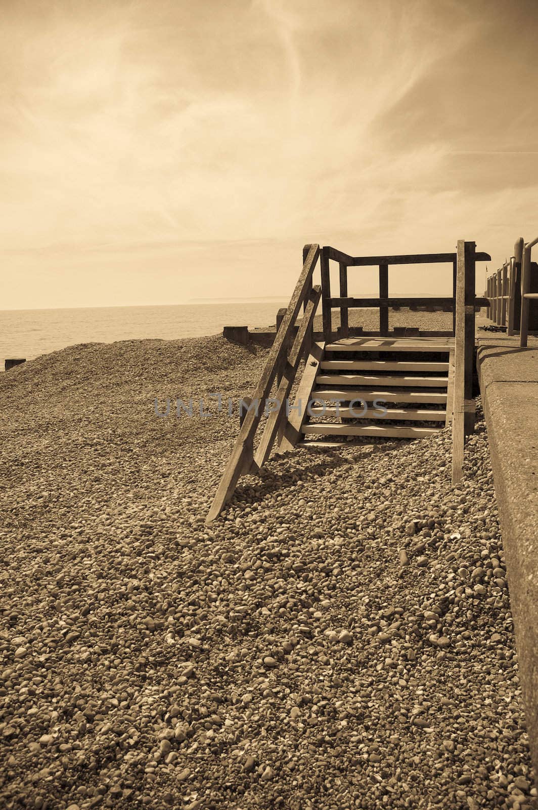 A sepia toned image of a seafront with some old wooden steps