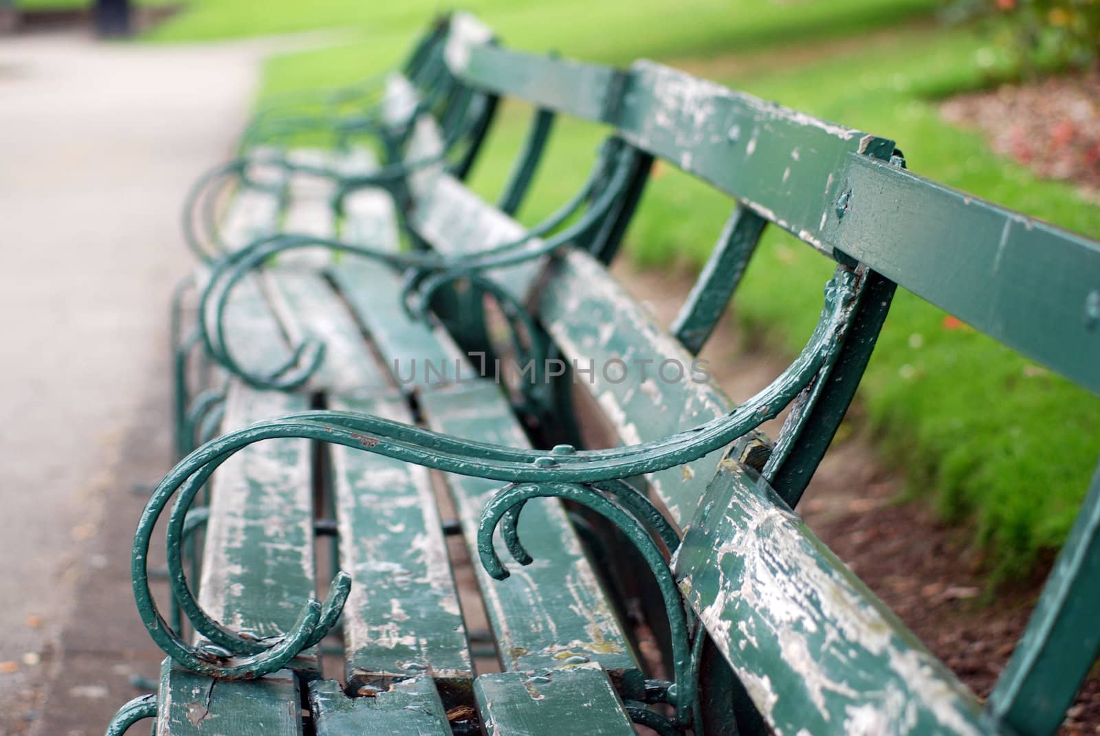 A photograph of a row of green benches with peeling paint