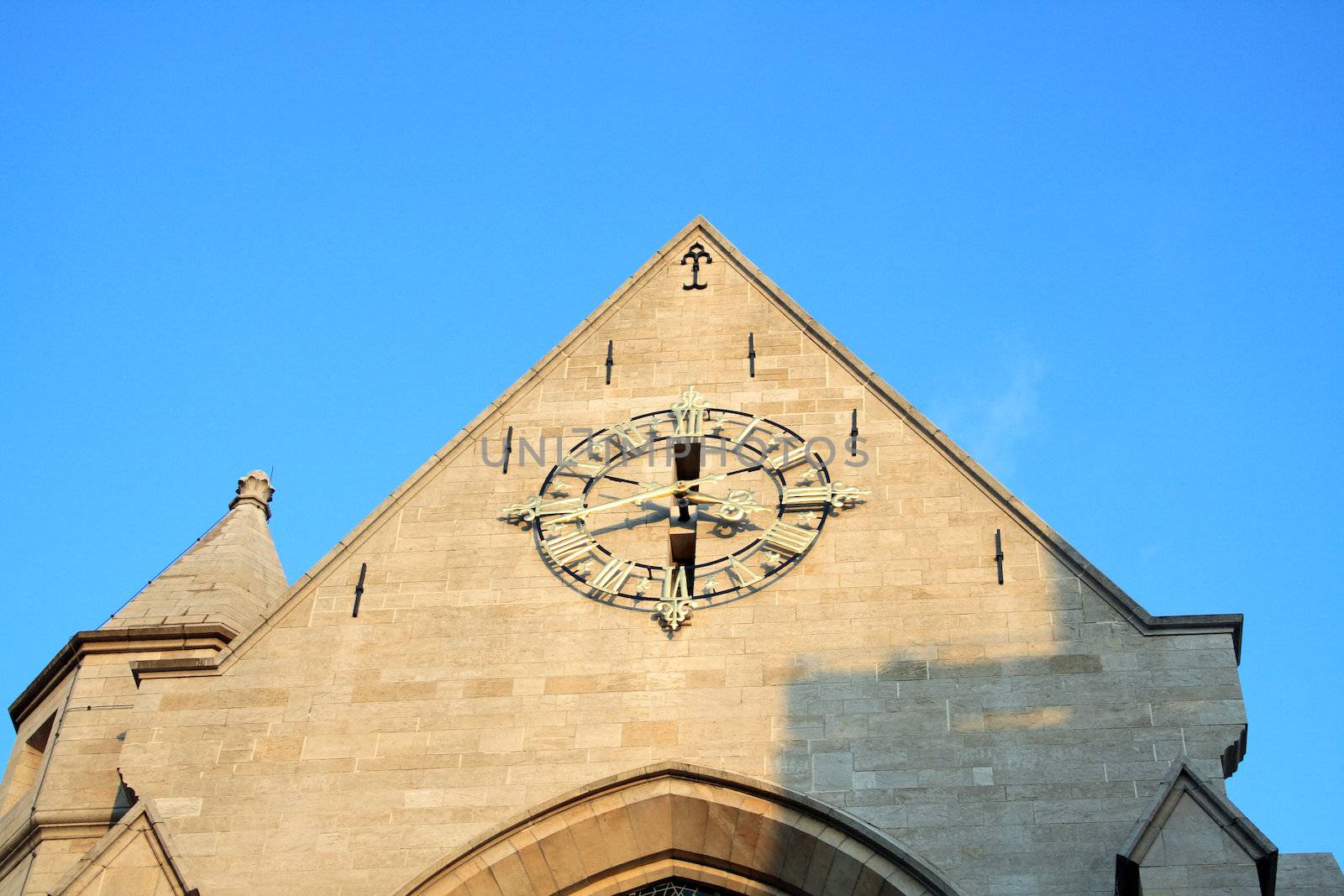 Antique clock at the chirch wall on blue sky background