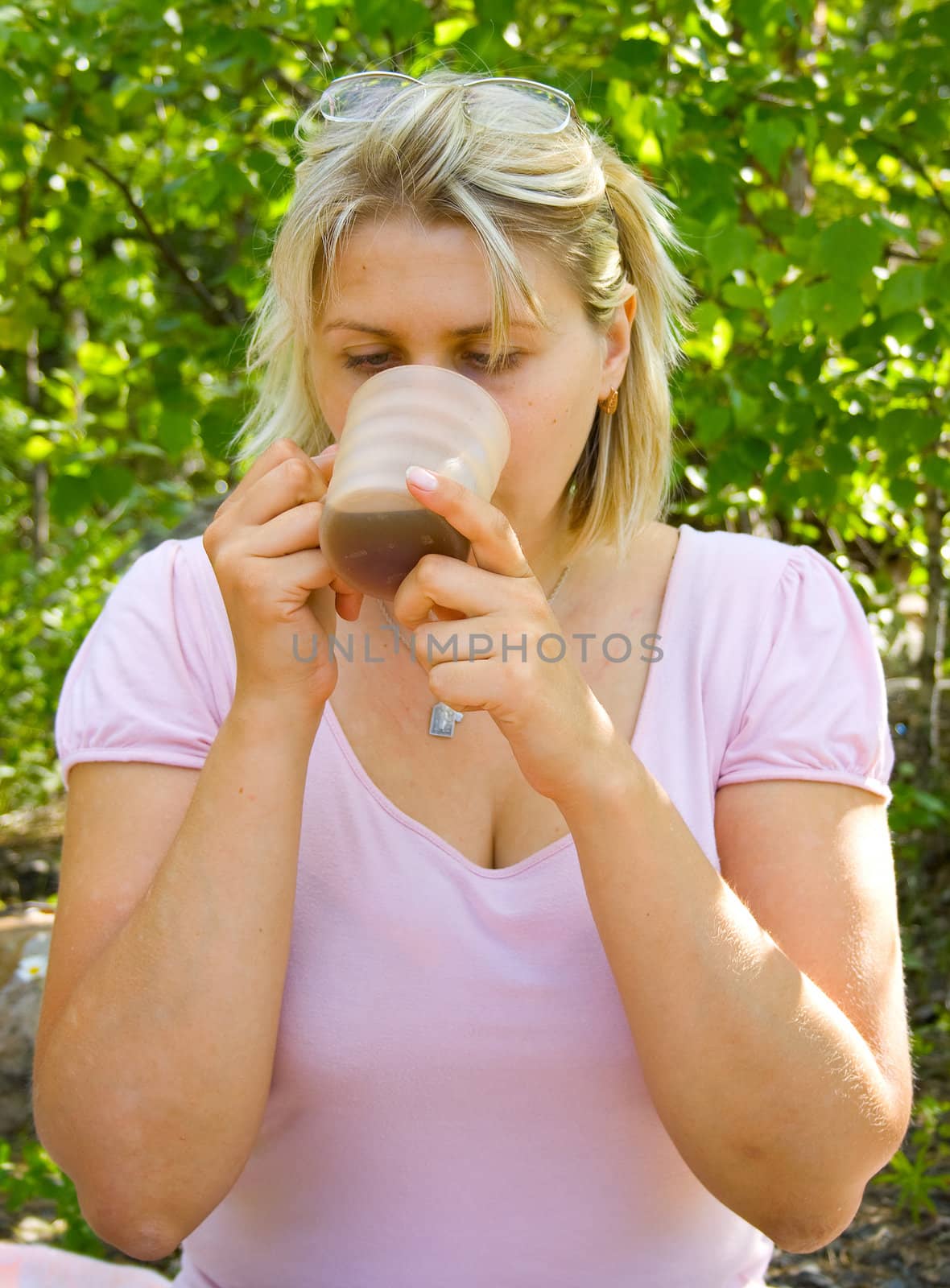 The woman drinks tea from a cup on picnic