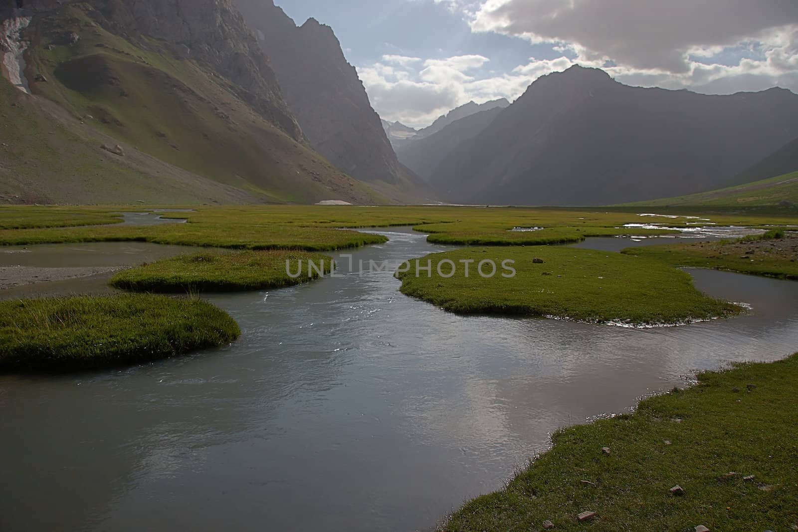 Slow mountain river with grassy islands, Tajikistan.