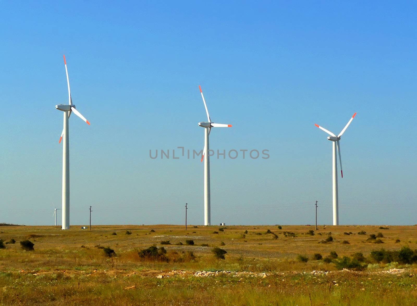 three windmills in a green field and blue sky in the background