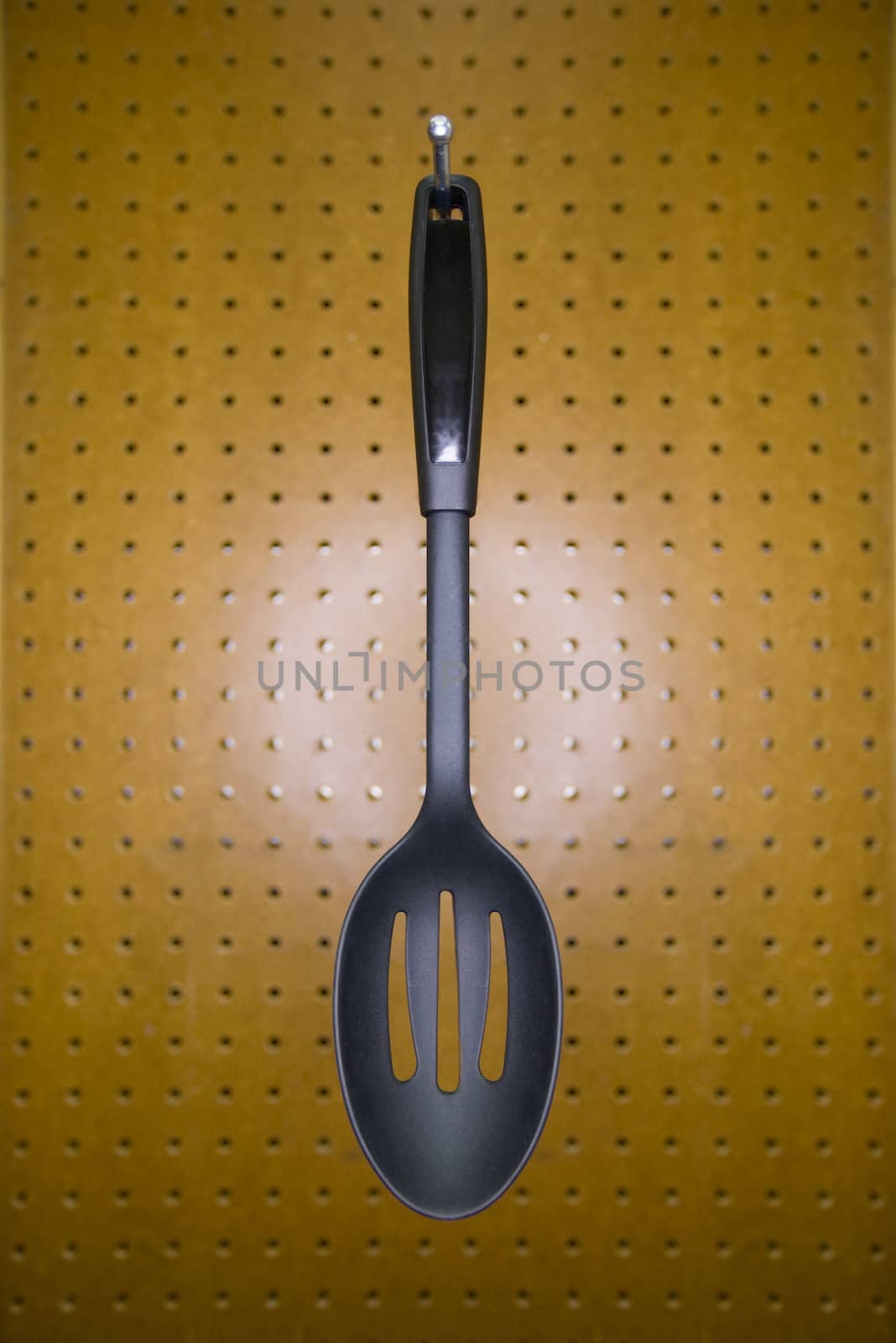 Slotted cooking spoon on a pegboard hook