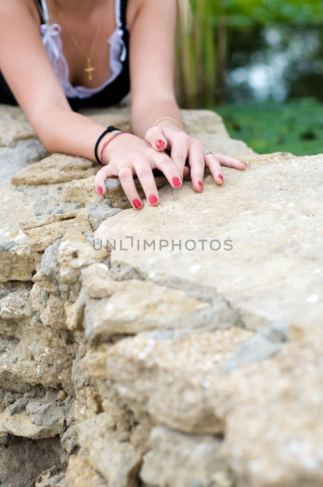 young girl lying at stone, just hands and breast are visible