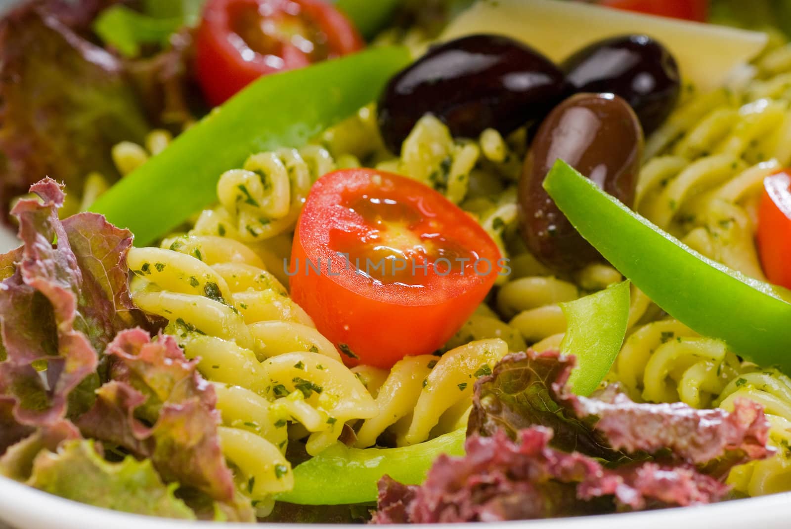 fresh healthy homemade italian fusilli pasta salad with parmesan cheese,pachino cherry tomatoes, black olives and mix vegetables ,dressed with extra-virgin olive oil and pesto sauce