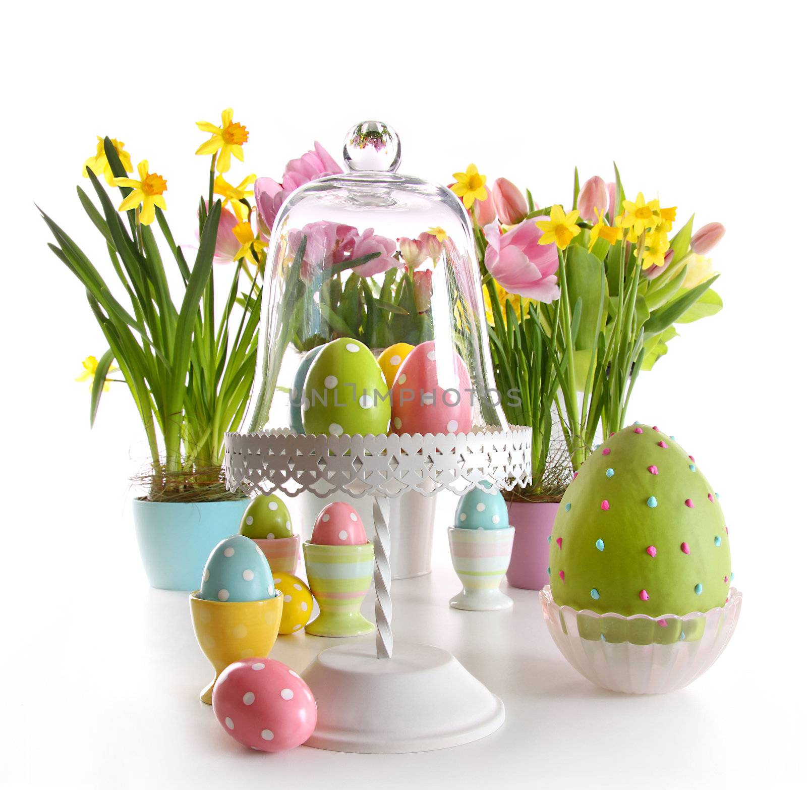 Easter eggs on cake stand with spring flowers on white