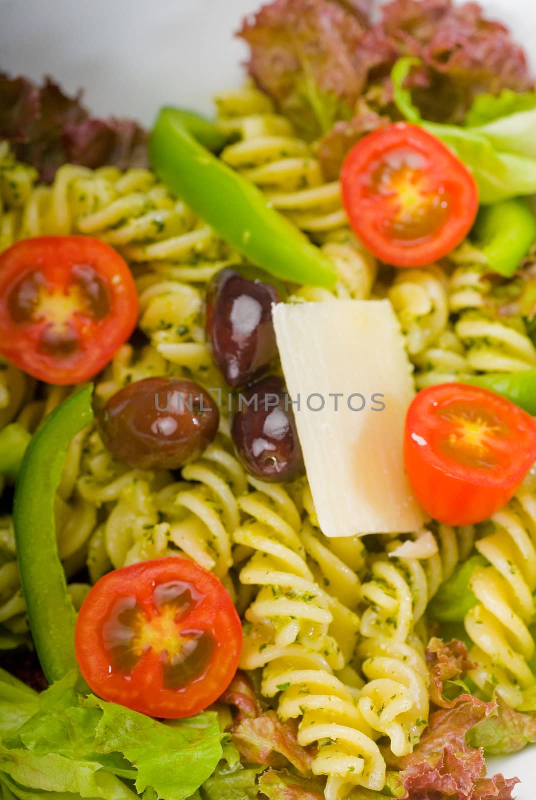 fresh healthy homemade italian fusilli pasta salad with parmesan cheese,pachino cherry tomatoes, black olives and mix vegetables ,dressed with extra-virgin olive oil and pesto sauce