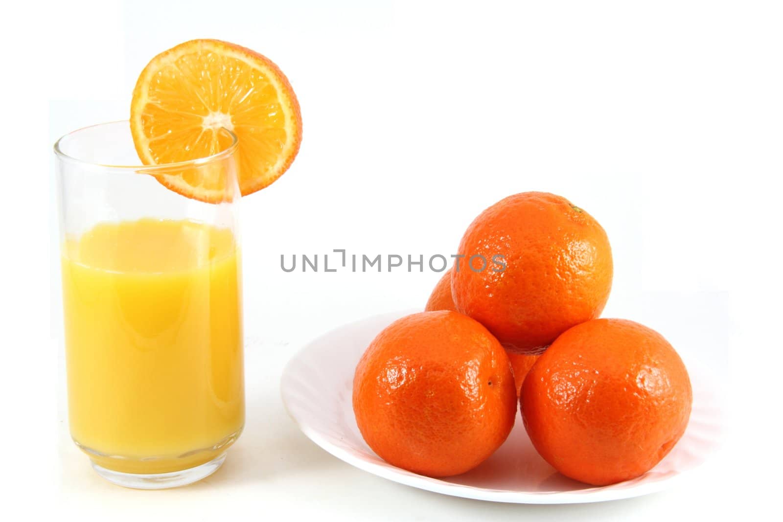 Glass of orange juice with oranges on the side.
