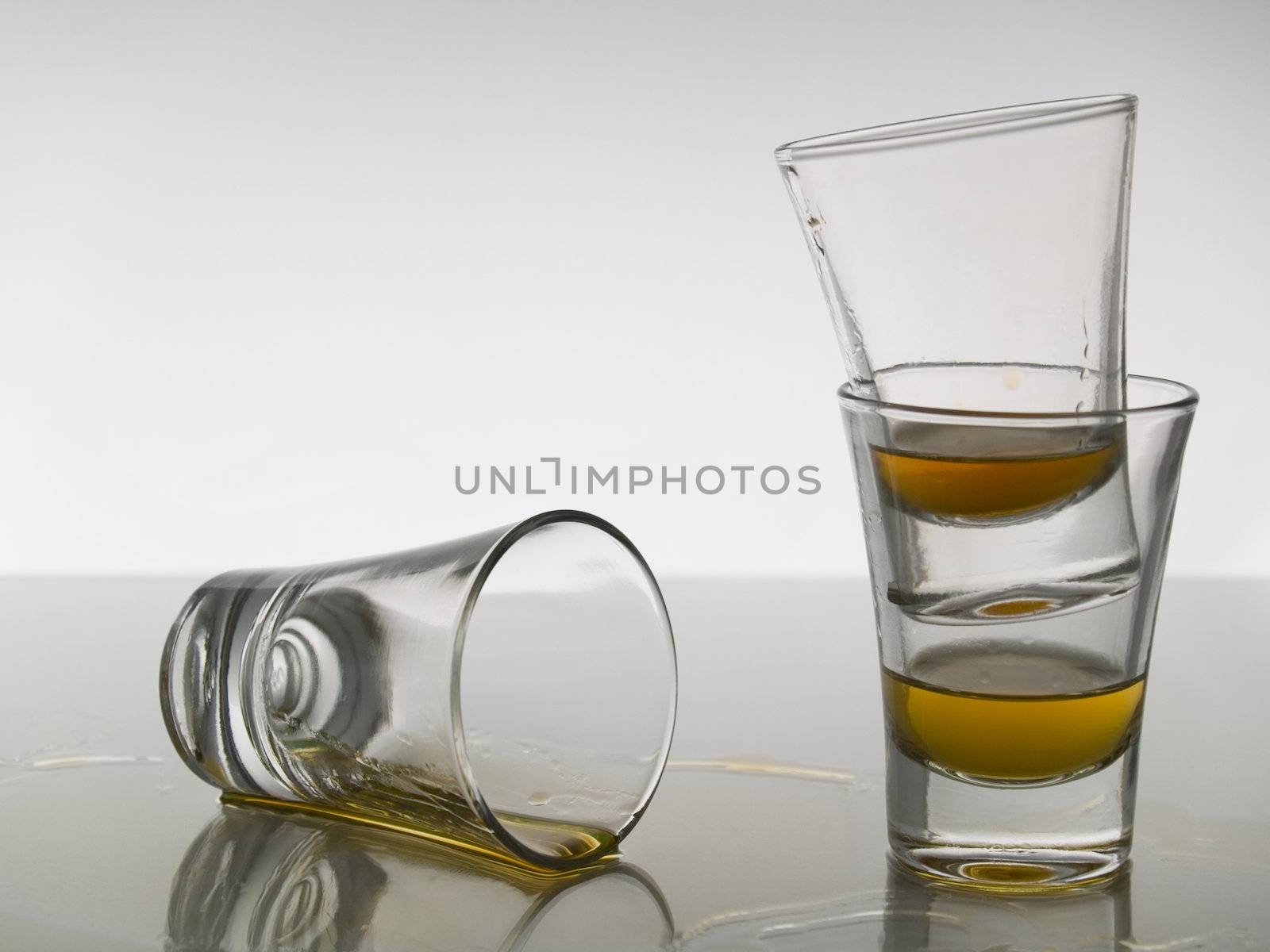 Three shots of whiskey on gray background over gray floor.