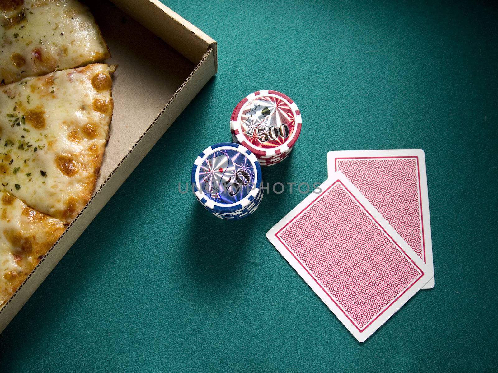 Two cards, two piles of chips and a box of pizza over a green felt.
