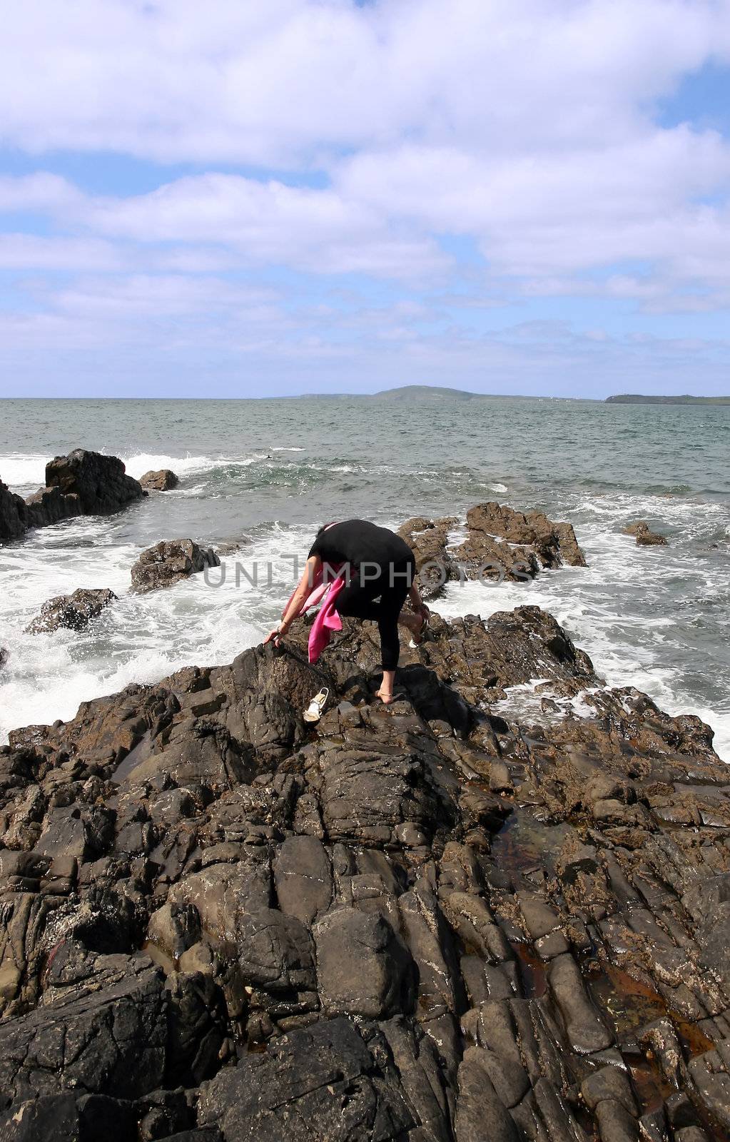 woman with high heels on the rocks at the waters edge with a silk scarf fitting on her high heels