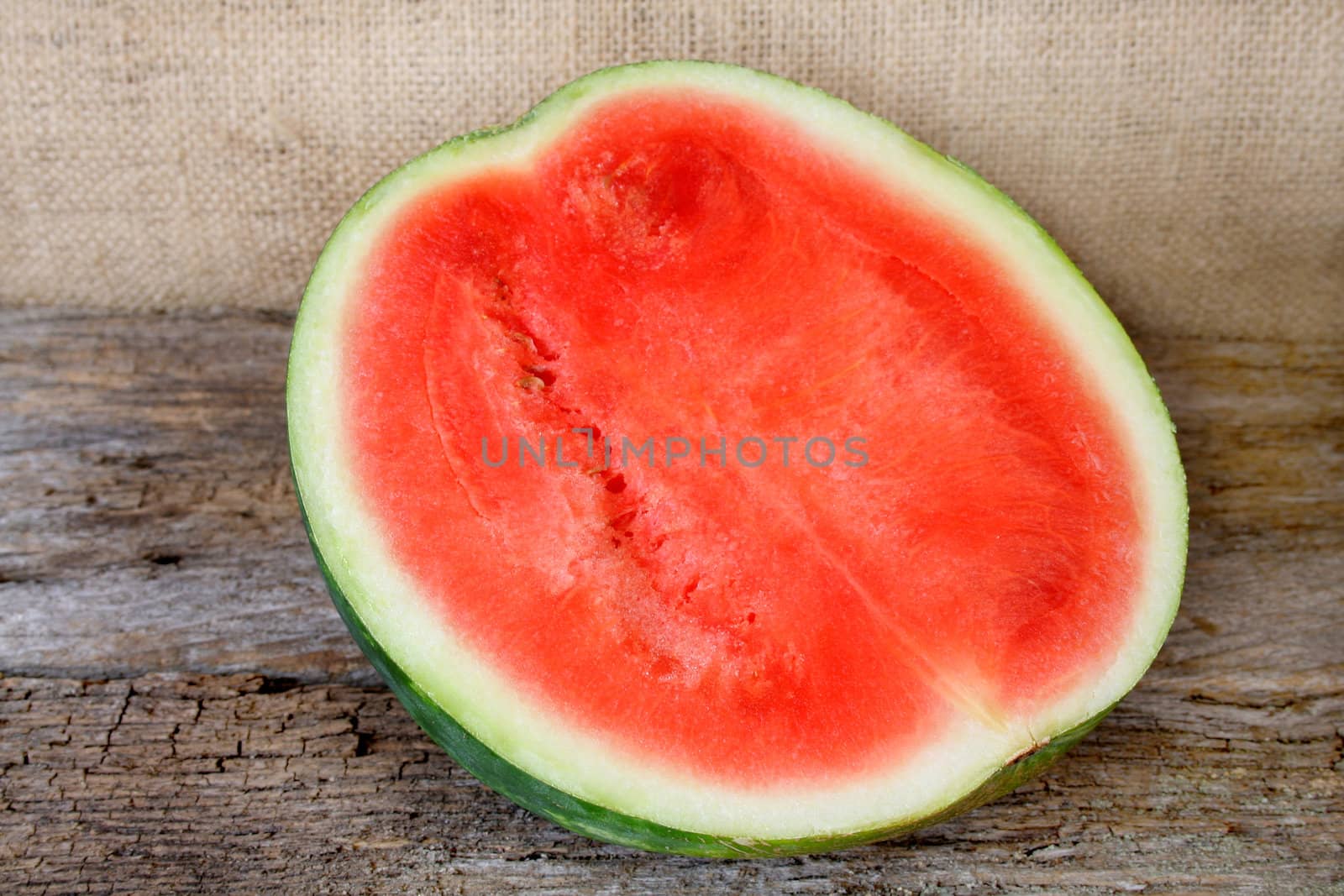 Half of a watermelon on a wood textured background.