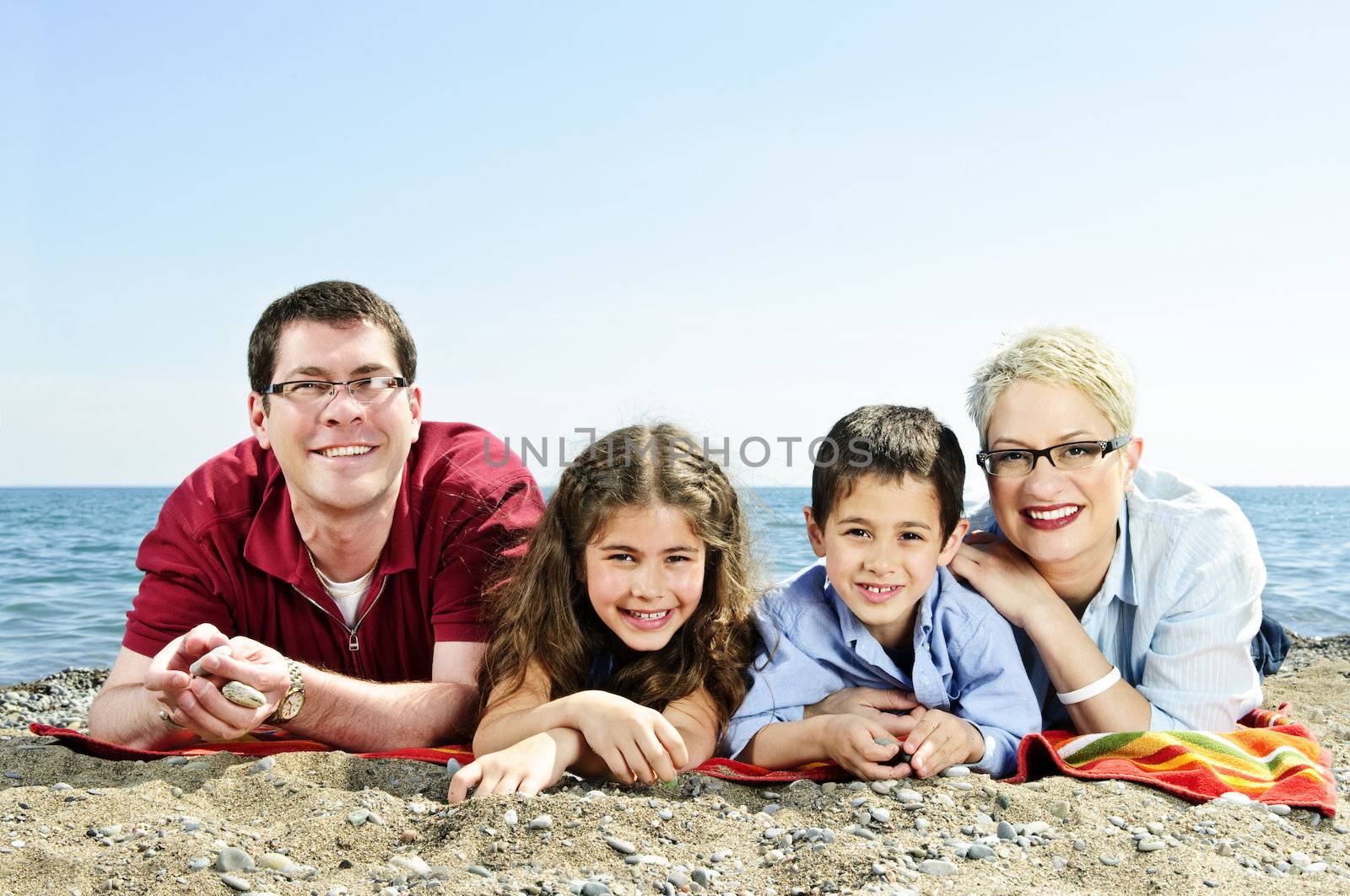 Happy family laying on towel at sandy beach