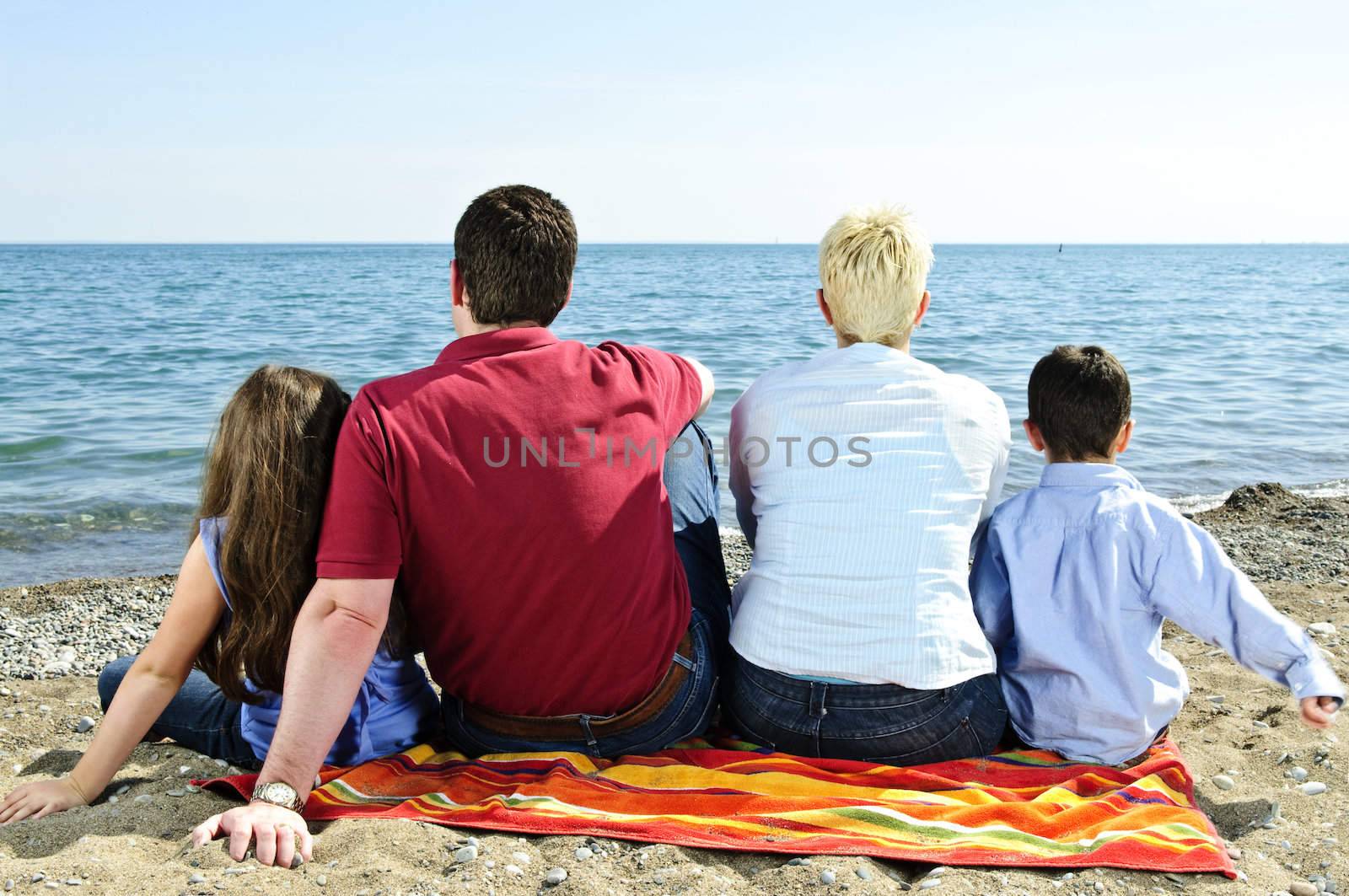Family sitting on towel at sandy beach