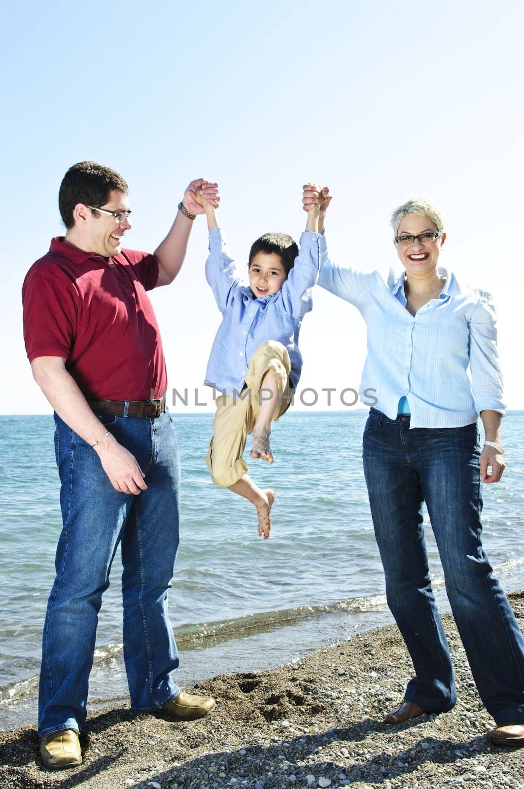 Portrait of parents lifting boy playfully at beach
