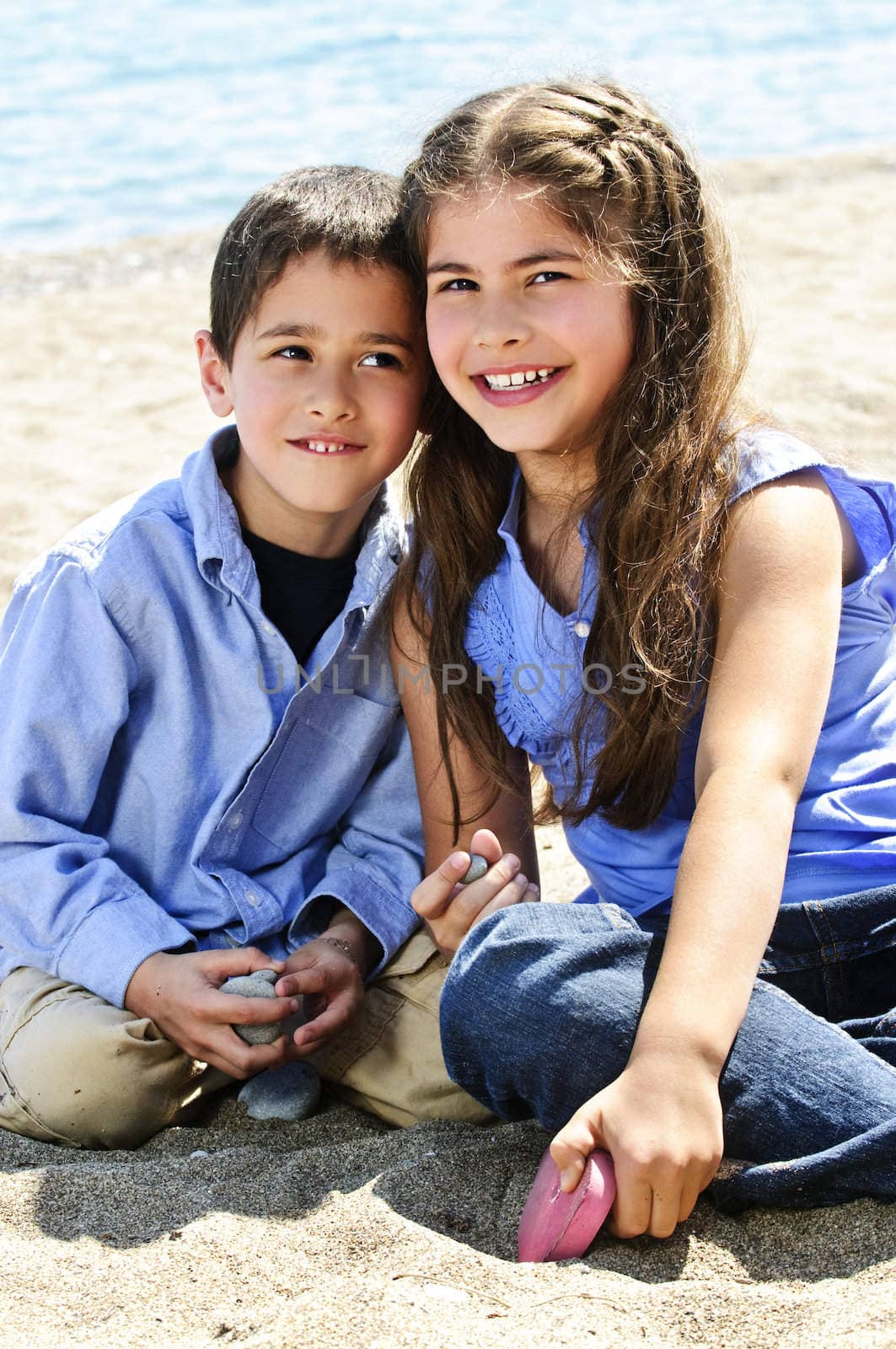 Portrait of brother and sister sitting on sand at the beach