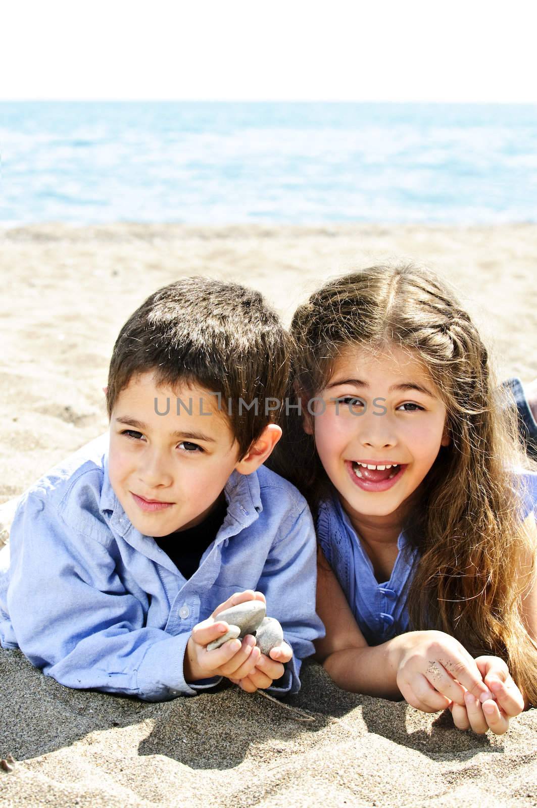 Portrait of brother and sister playing in sand at the beach