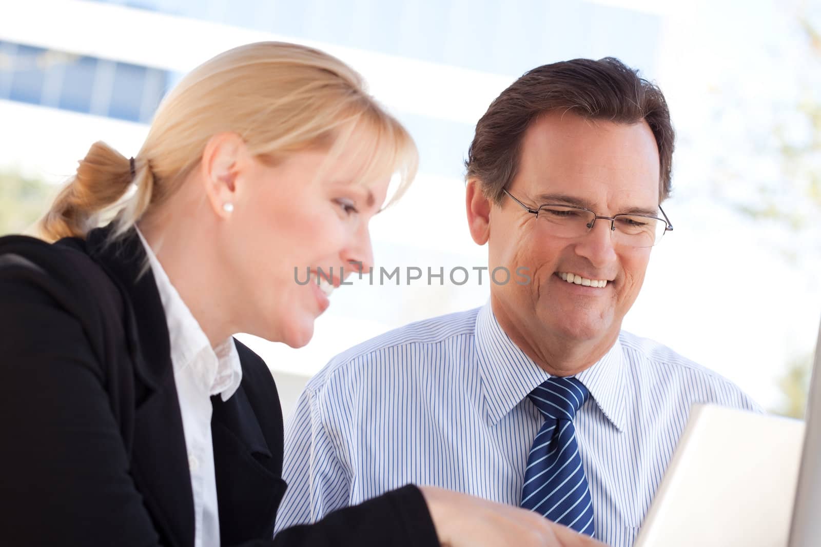 Handsome Businessman Laughs While Working on the Laptop with Female Colleague Outdoors.