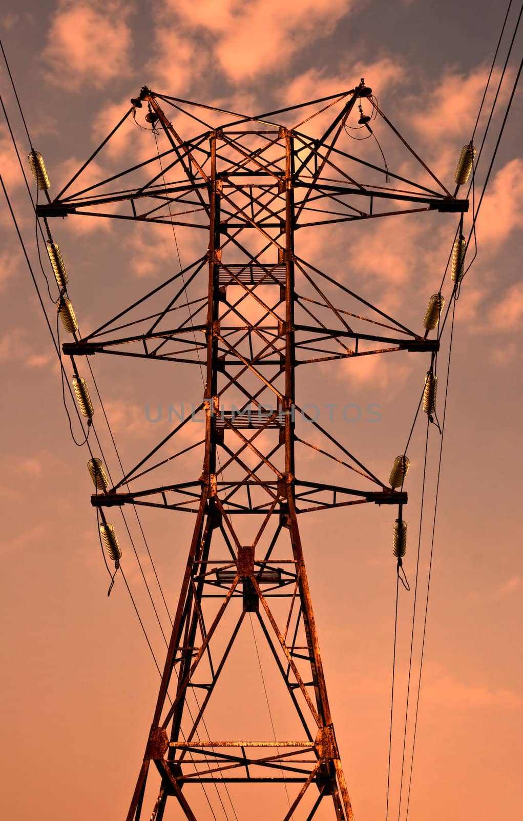 Power transmission pole against sunset skies