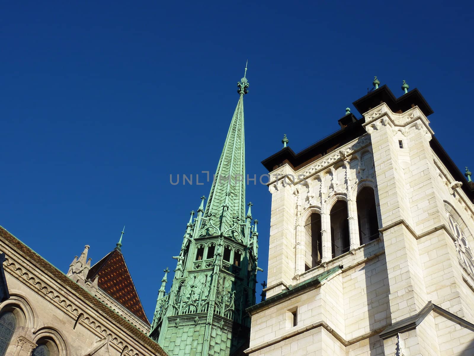 Green bell-tower of Saint-Pierre's cathedral in Geneva, Switzerland surrounded by old constructions