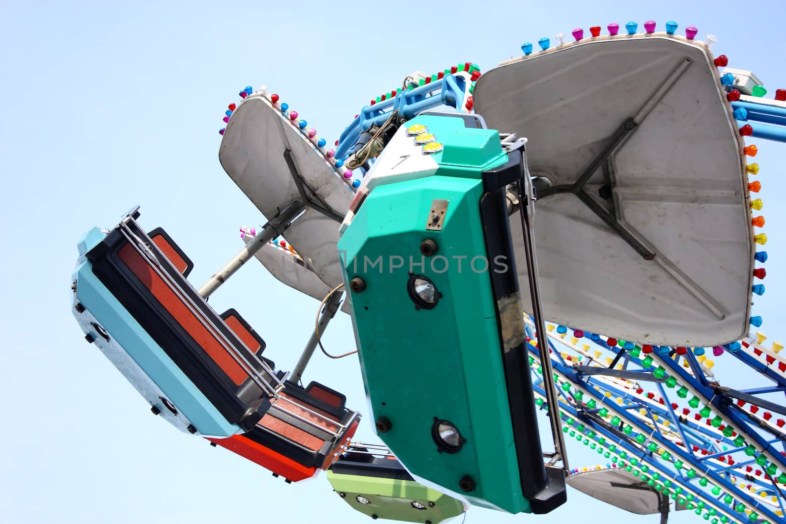 Child attraction in park merry-go-round in front of the blue sky