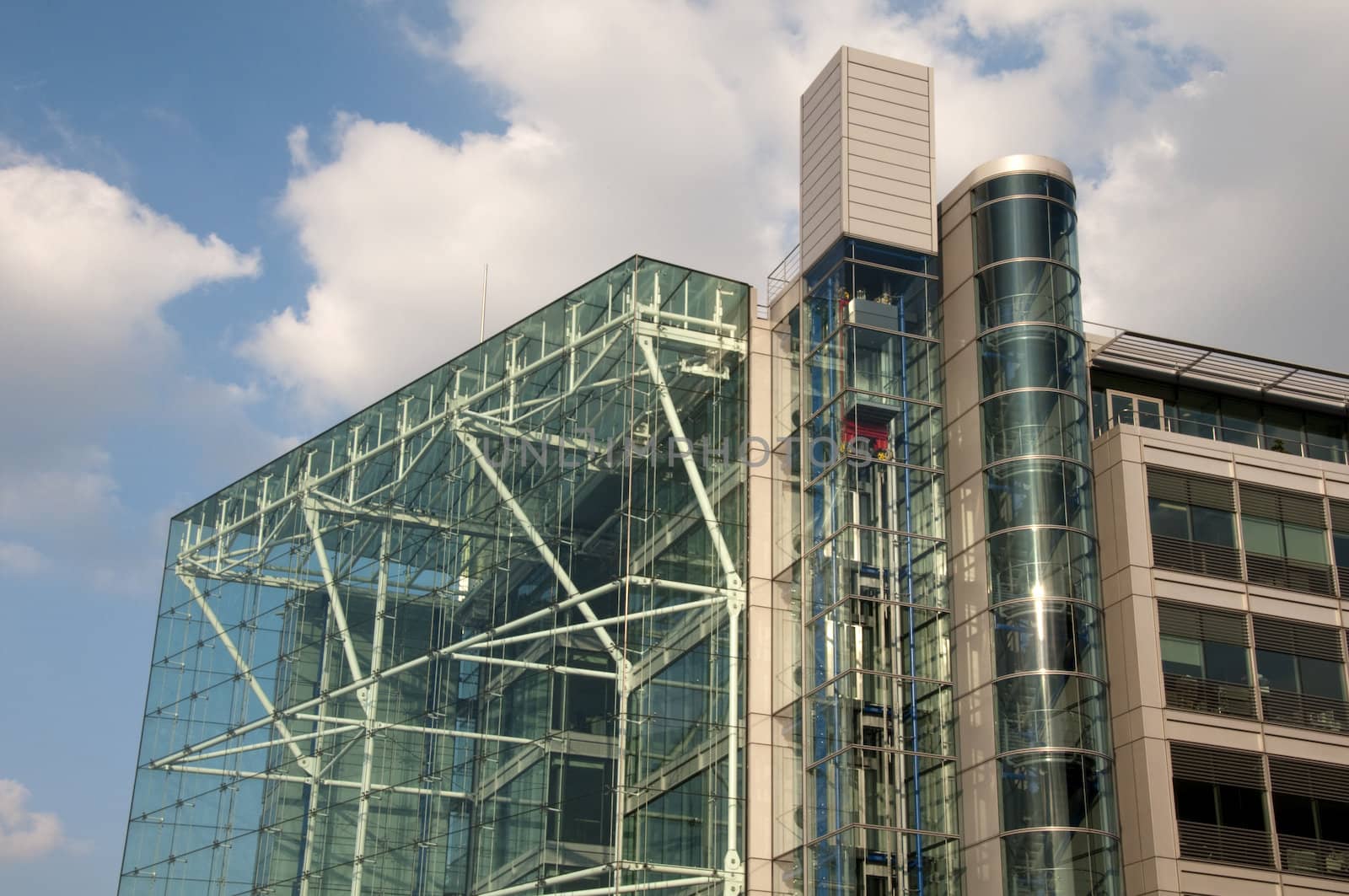 A glass office building in london with a cloudy blue sky