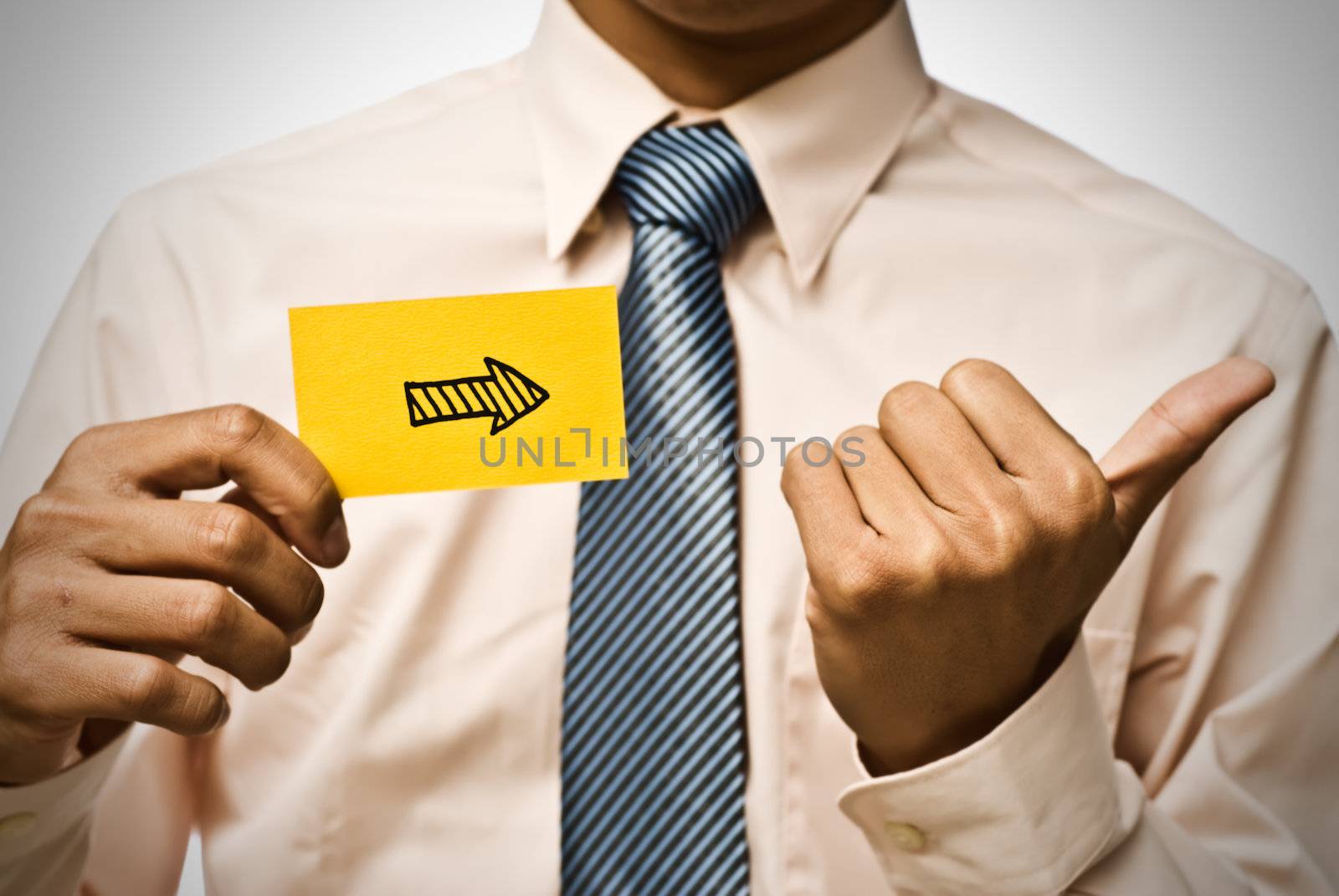 Arrow shape on yellow card and hand gesture by businessman.