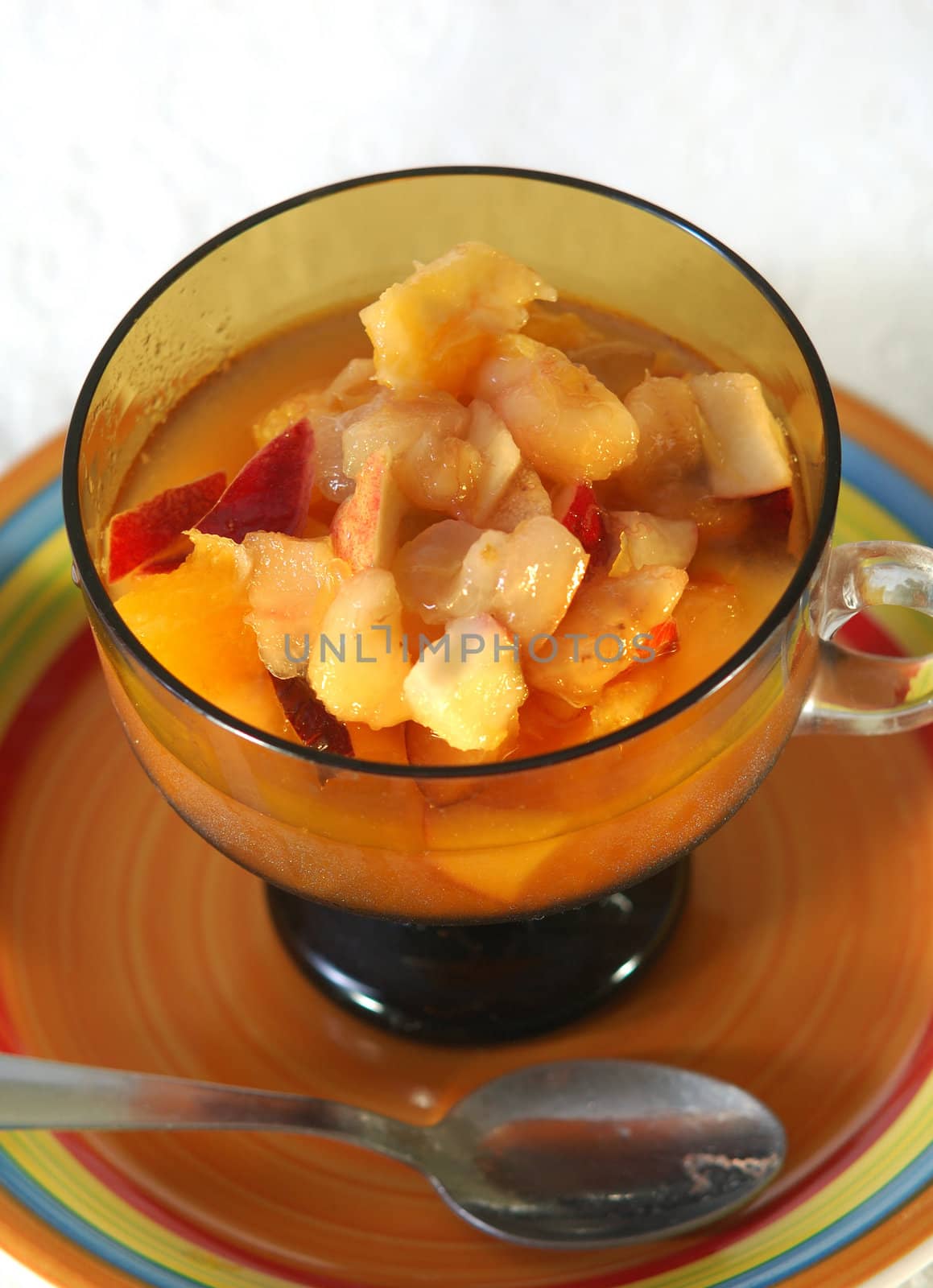 close up of a bowl containing fresh fruit salad and a spoon
