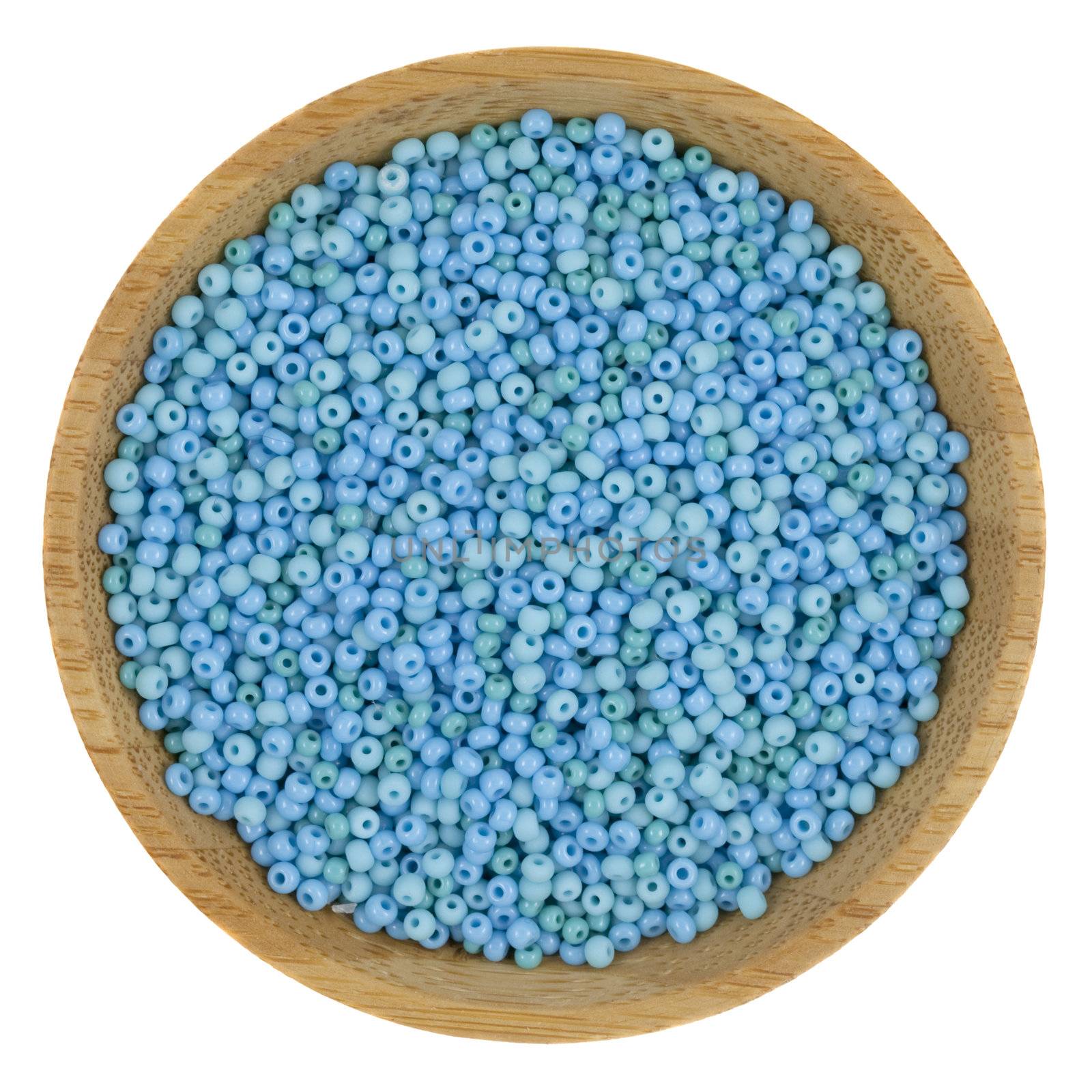 macro shot of small, blue and green, glass beads on a small wooden bowl, isolated on white
