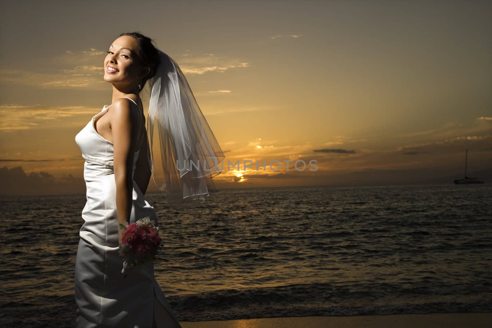 Young adult female Caucasian bride on beach.