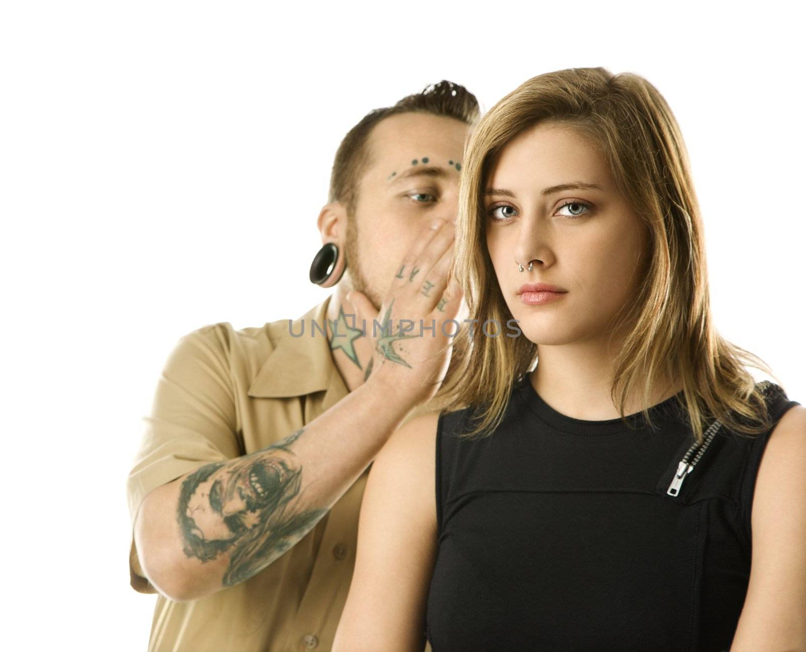 Caucasian mid-adult man whispering into ear of teen female.