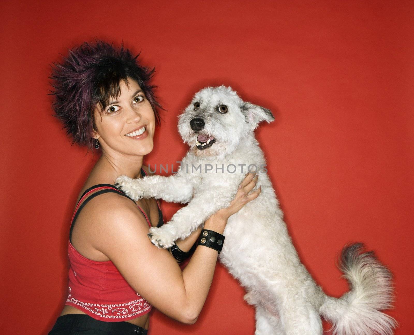 Hispanic young adult female holding small white dog.