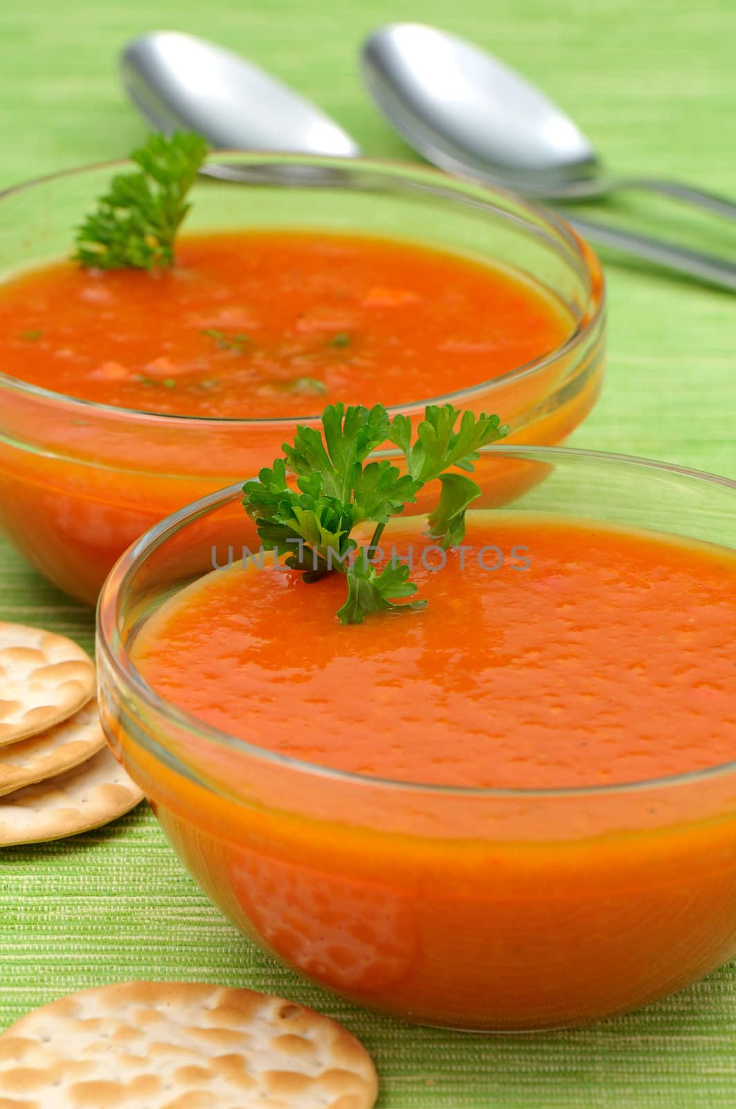 Two bowls of tomato soup with parsley and cheese crackers