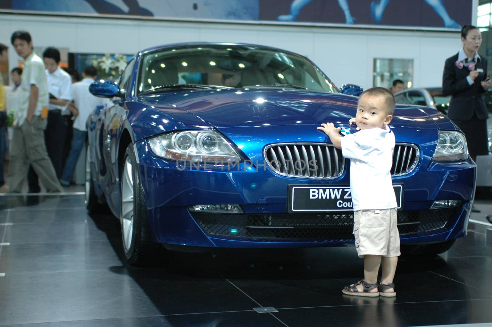 China, Shenzhen Moto - car show in exhibition center. Visitors watching European, American and Chinese cars. Crowd of people interested in newest moto technology. Kid playing with new BMW car.