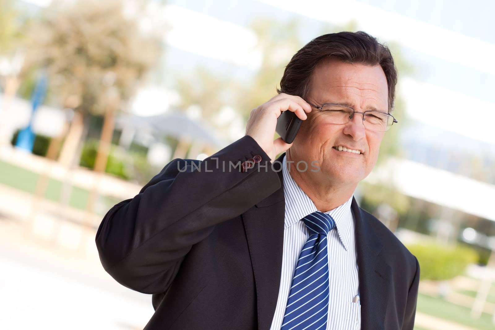 Confident, Handsome Businessman Smiles as He Talks on His Cell Phone.