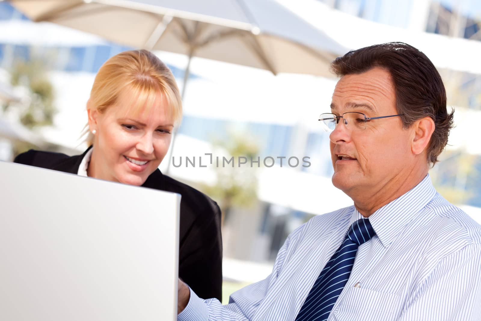 Businessman and Female Colleague Using Loptop Outdoors by Feverpitched