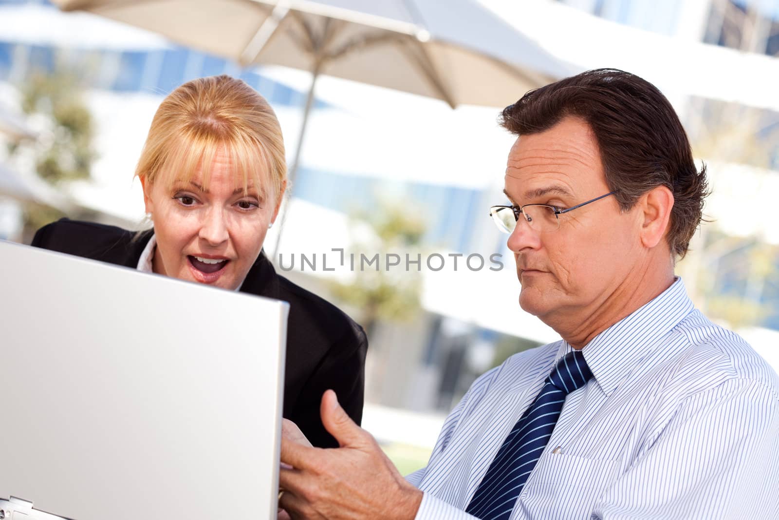 Businessman and Female Colleague Using Loptop Outdoors by Feverpitched