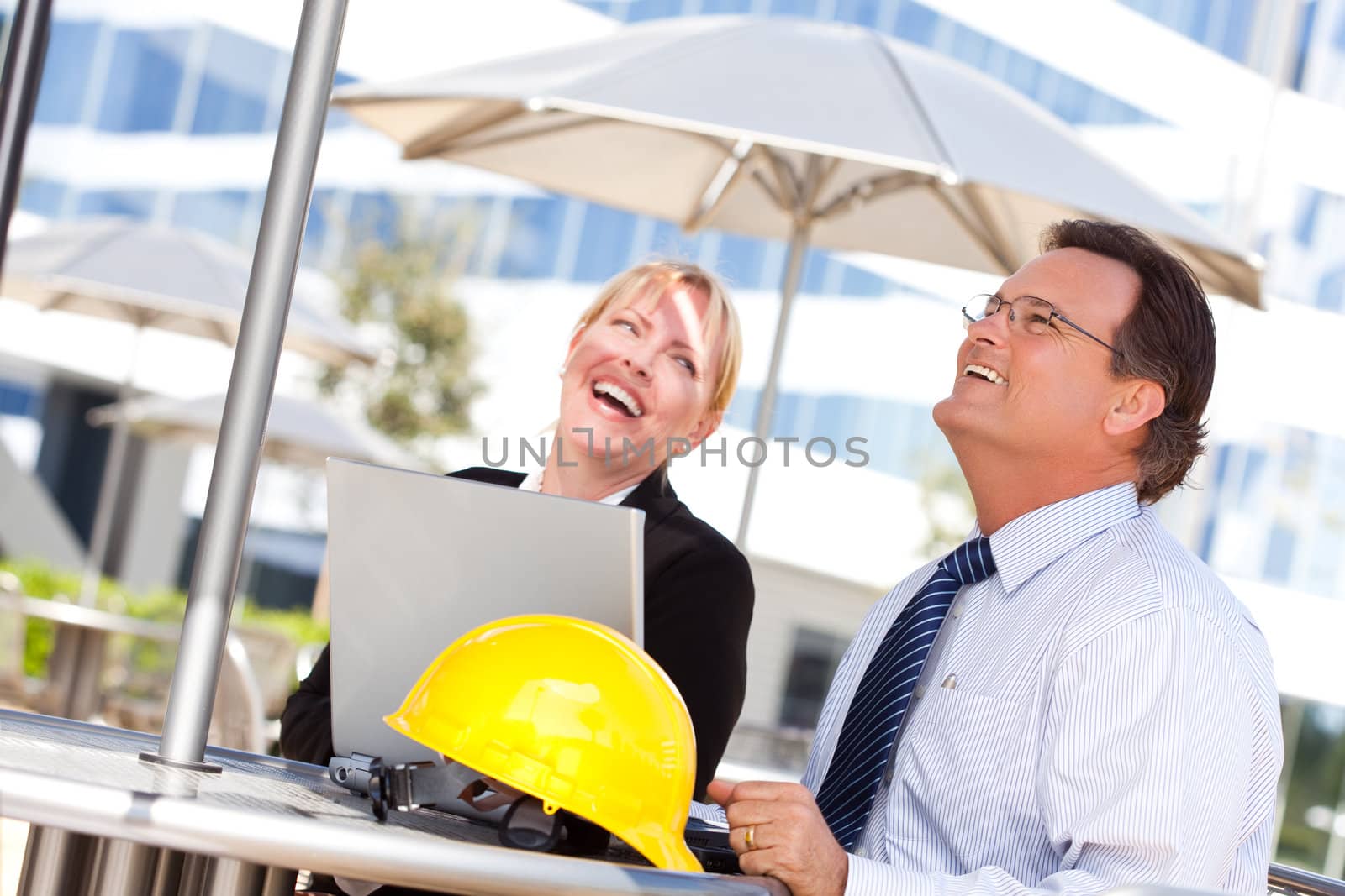 Handsome Businessman and Attractive Businesswoman Laughing While Working on the Laptop Outdoors.
