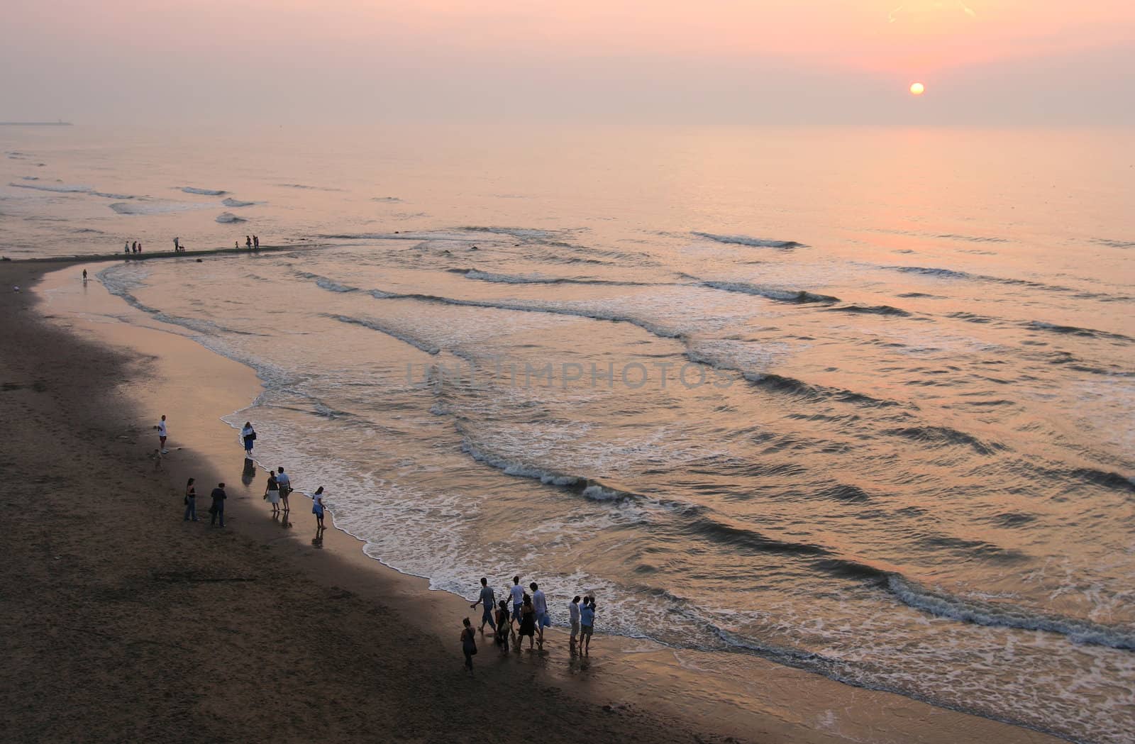 People walking on the beach in the sunset on a summer evening