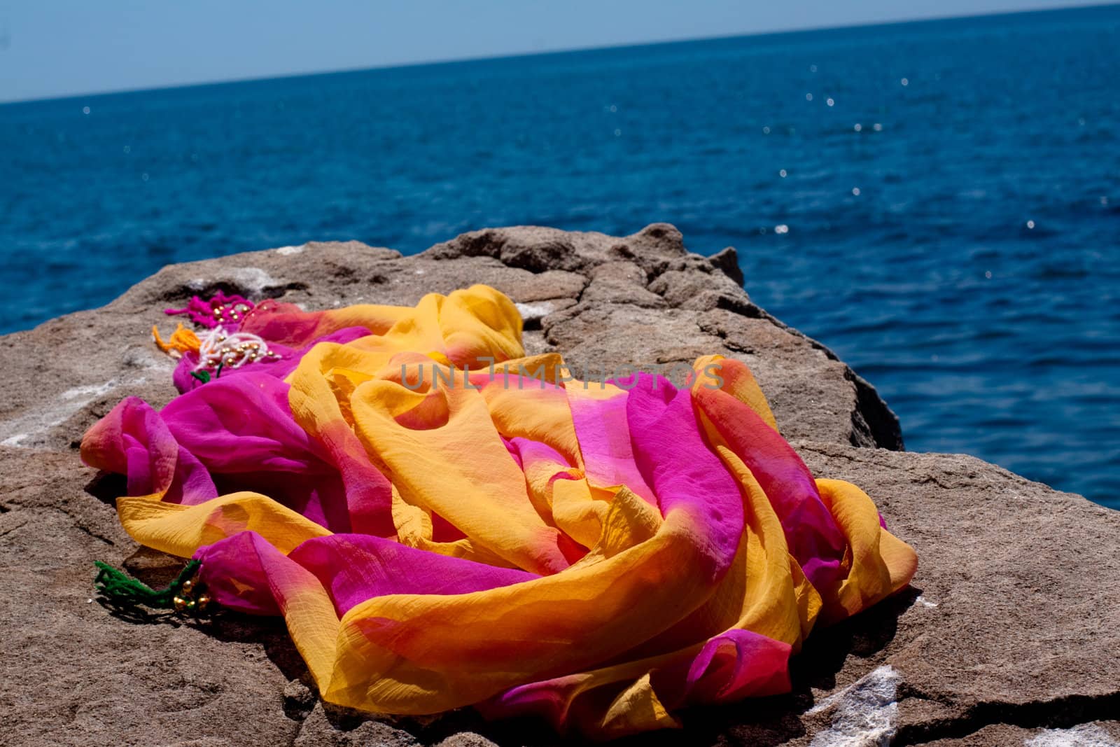 red and orange scarf on stone near sea
