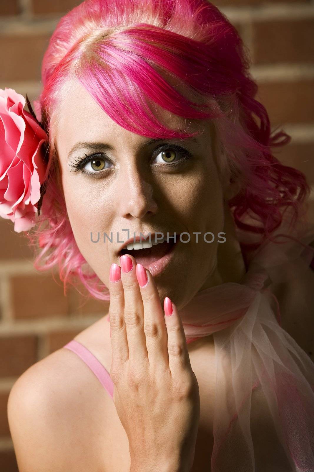 Pretty woman with flower in her hair on brick background